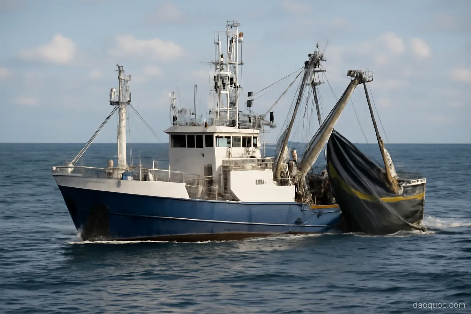 a large tuna fishing vessel with nets and cranes on deck in open ocean