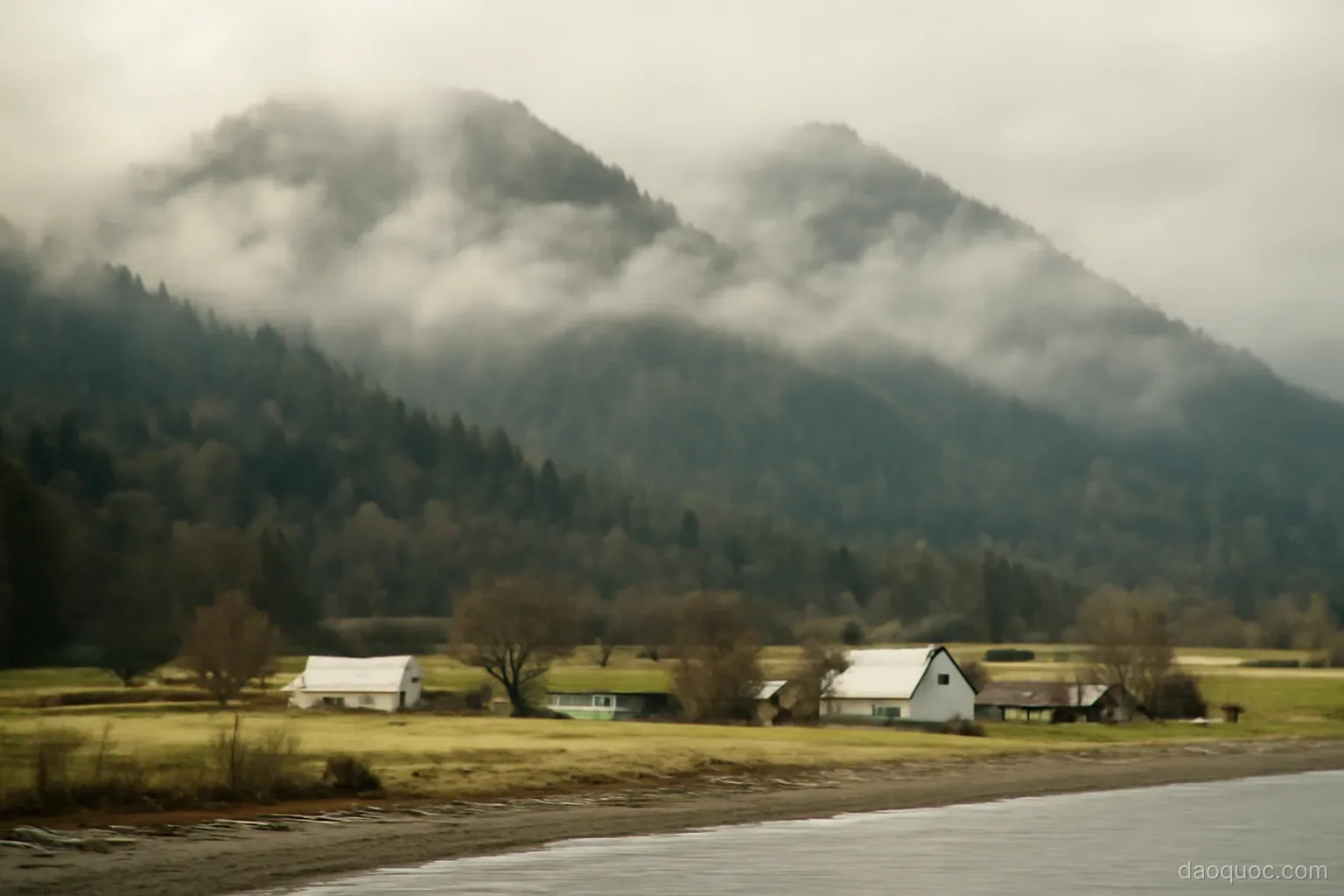 misty forested mountains rising behind a coastal plain with small farms