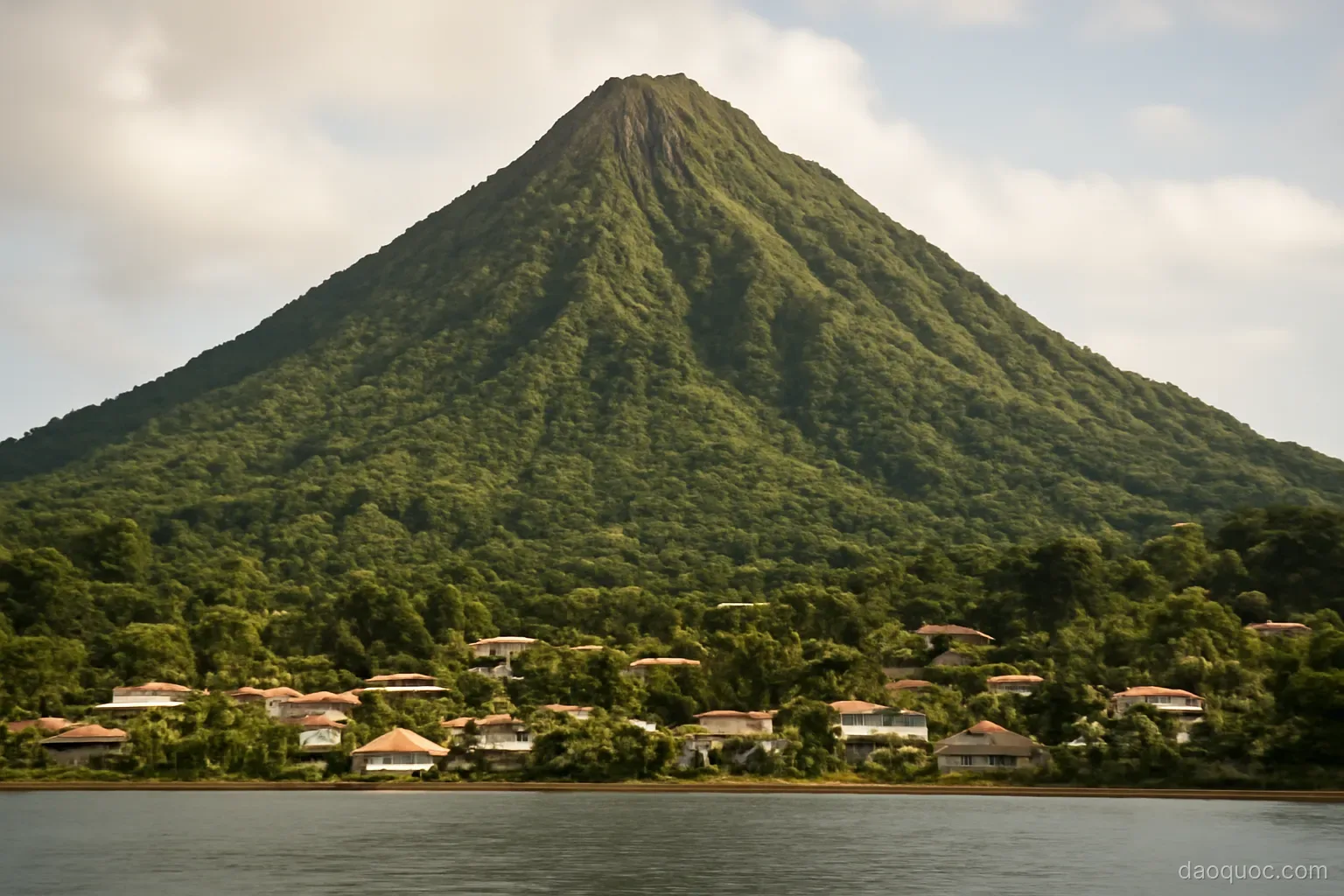 a steep volcanic peak covered in rainforest rising above a coastal village